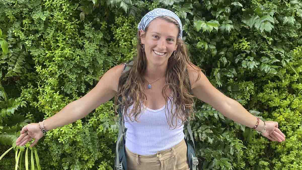 A woman with arm stretched out in front of vines